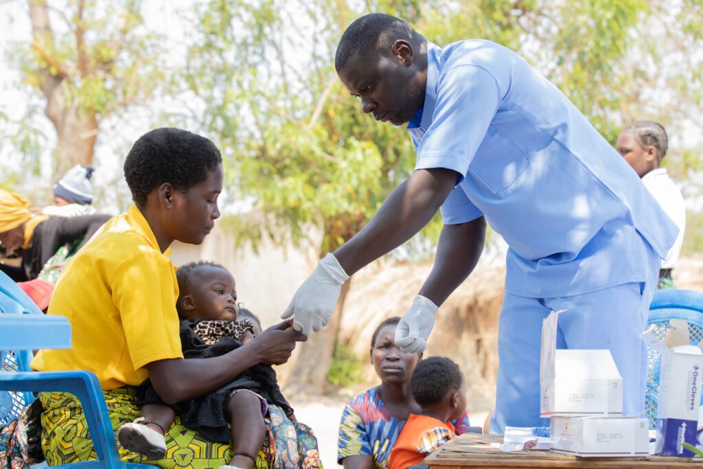 A community health worker providing care to a caregiver holding a child
